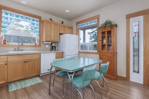 A kitchen with wooden cabinets, a white refrigerator, a coffee maker, a sink, and a dining table with chairs.