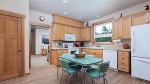 Une cuisine compacte avec des meubles en bois, un réfrigérateur blanc, une table à manger avec des chaises et une fenêtre donnant sur un beau paysage.