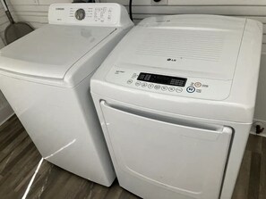 Two stacked washing machines, one Samsung and one LG, in a room with a tiled floor.
