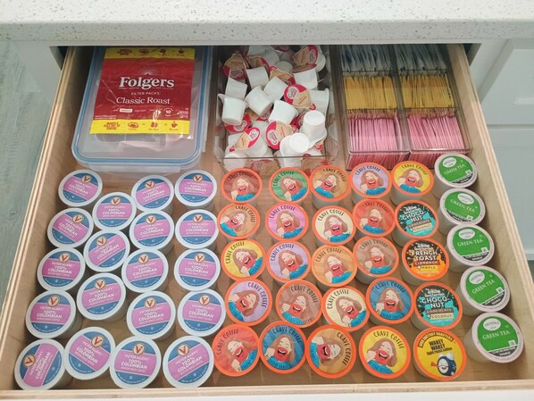 A drawer containing various coffee products including Folgers filter packs, Victor Allen Colombian coffee, and Twinings green tea.