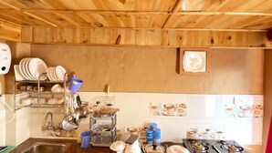 A kitchen with wooden ceiling beams, a sink, dish racks, and a window with a view.