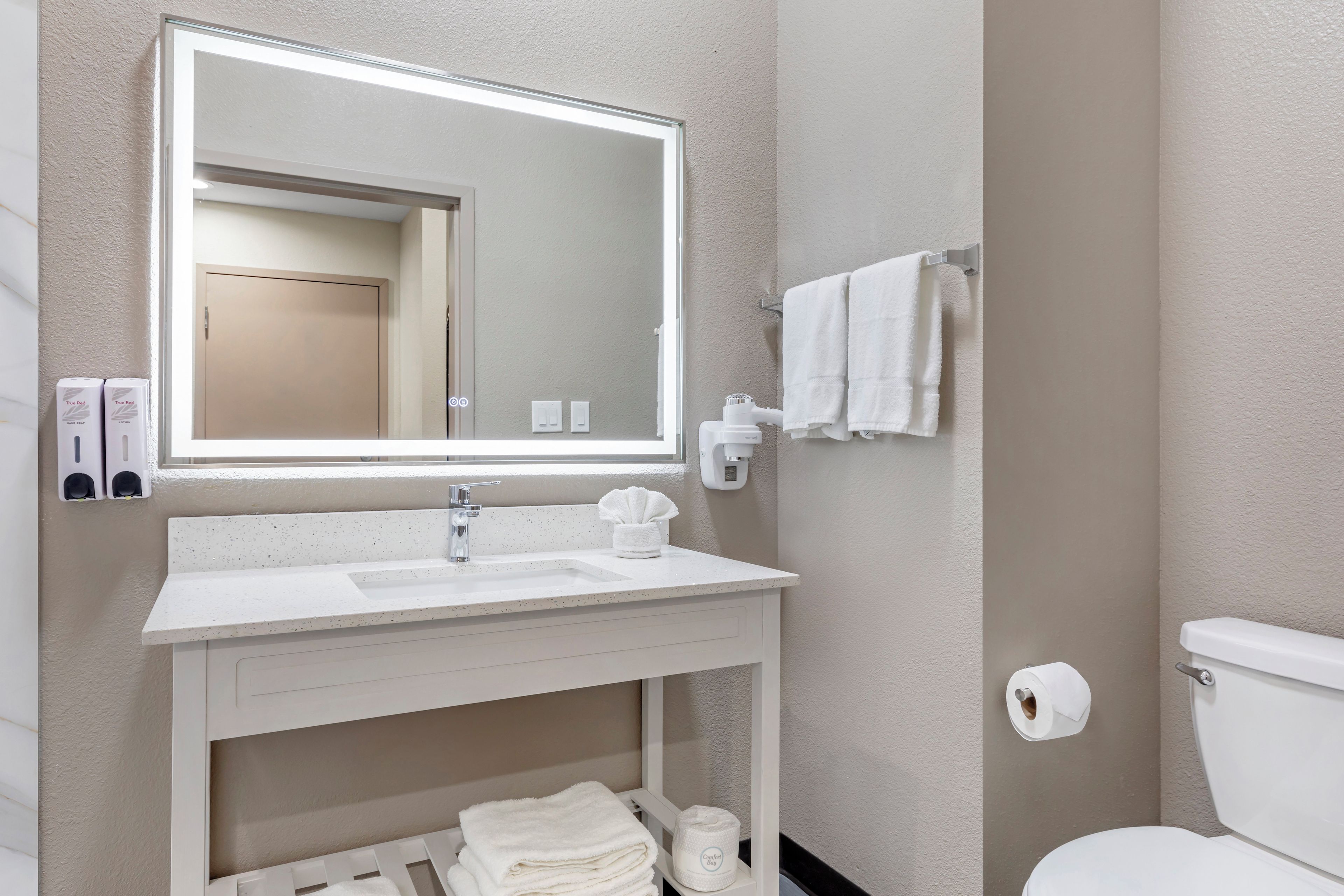 Ein Badezimmer mit Waschbecken, Spiegel, Handtuchhalter und Toilette.