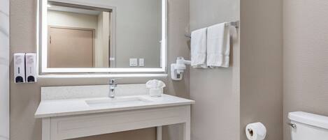 A bathroom with a white sink, mirror, towel rack, and toilet.