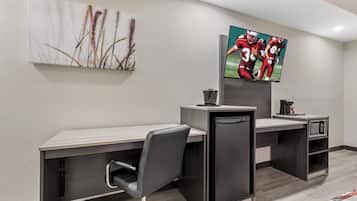 A modern office space with a desk, chair, and a flat-screen TV mounted on the wall.