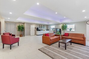 A spacious living area with a sofa, armchairs, a coffee table, and a kitchen in the background. - Red Roof Inn Hutchins (Hutchins)
