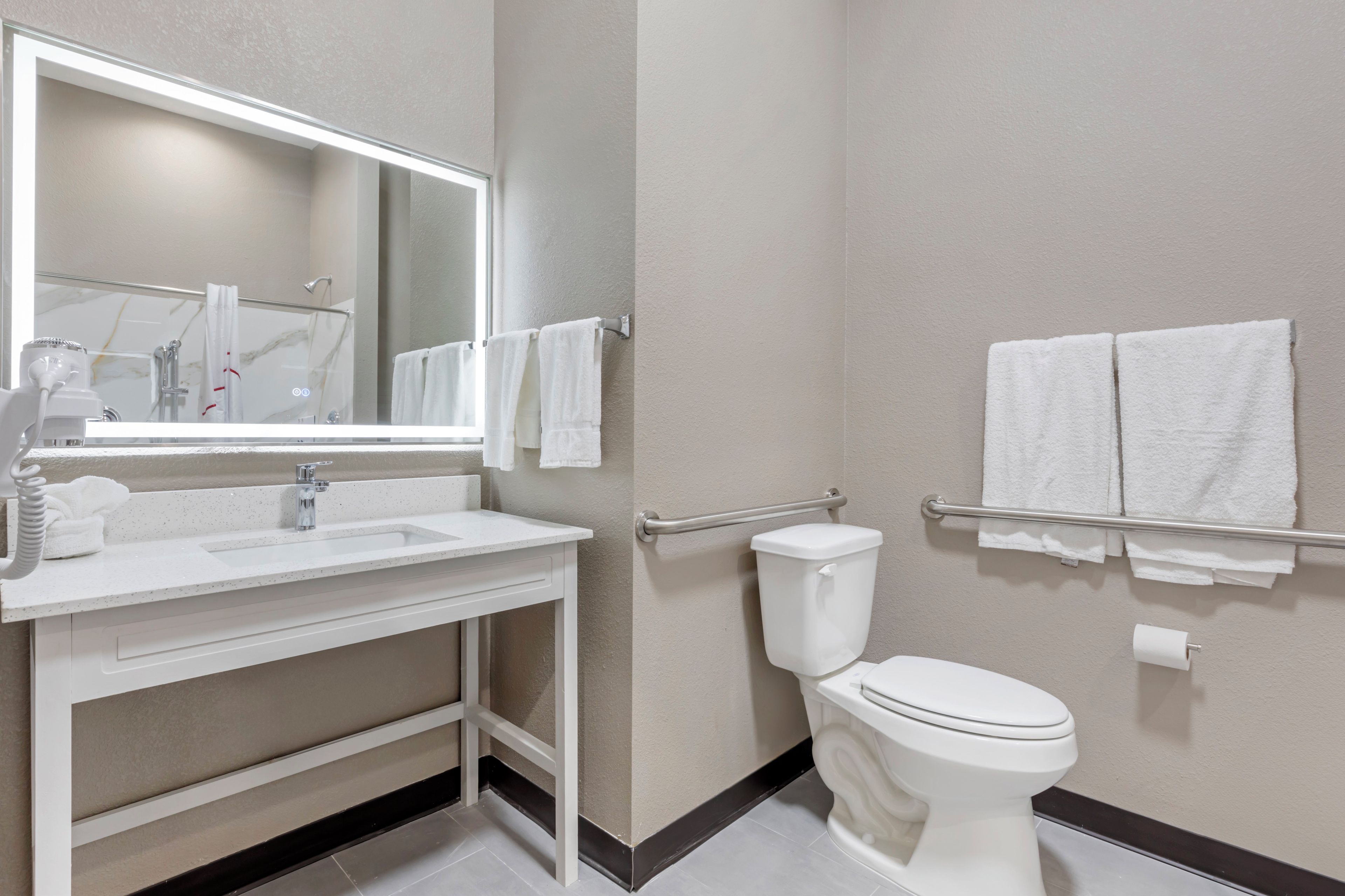 A modern bathroom with a white sink, mirror, and toilet.