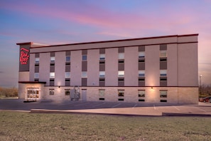 A Red Roof Inn building with a flat facade, multiple windows, and a parking lot in front. - Red Roof Inn Hutchins (Hutchins)