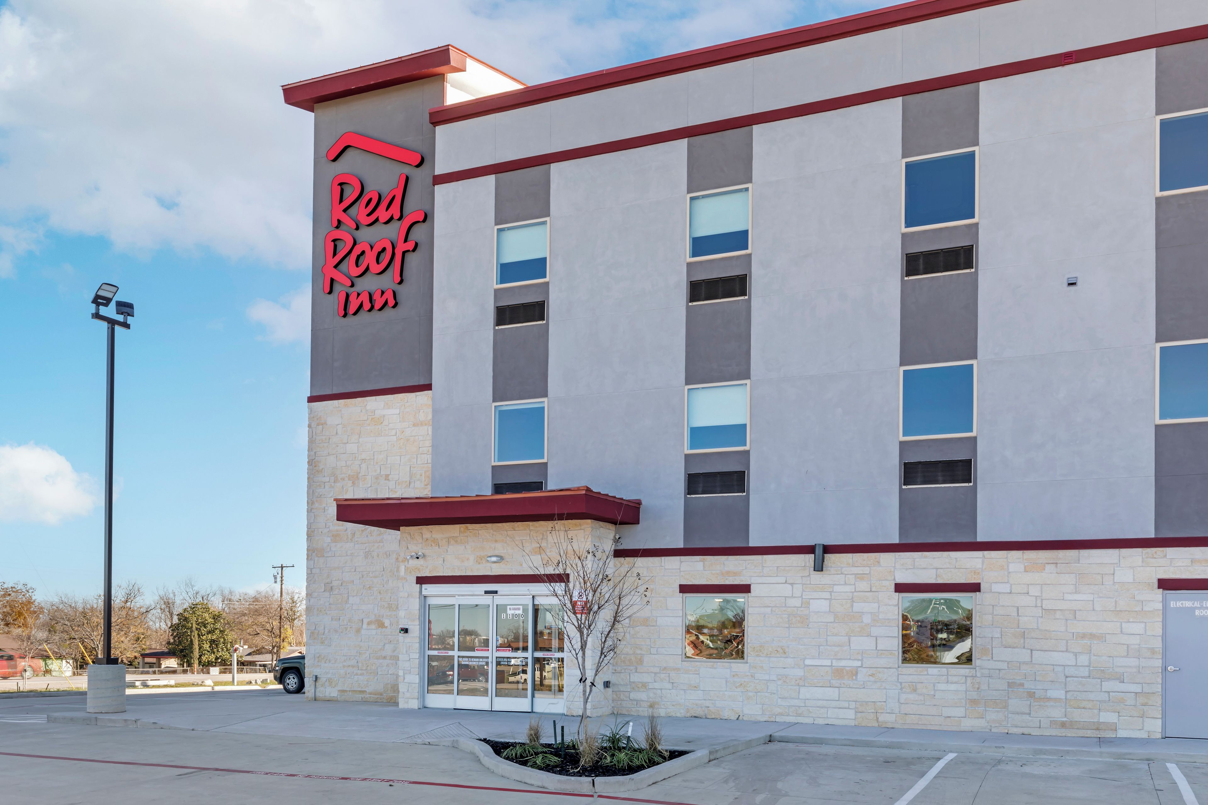 Een Red Roof Inn hotel met een stenen gevel, veel ramen en een heldere lucht.