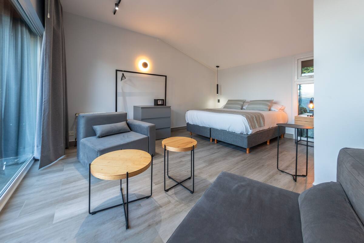 Ein modernes Hotelzimmer mit einem großen Bett, einer Couch, einem Couchtisch und einem Schreibtisch.