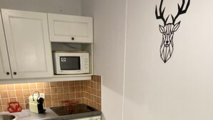 Ruokailutilassa on puinen pöytä, johon on katettu neljälle, valkoiset lautaset ja seinälle on kiinnitetty koristeellinen tarra, jossa on kuva peuran päästä.
