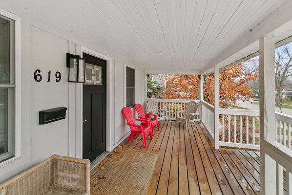 A porch with a wooden floor, a black door, and a mailbox.