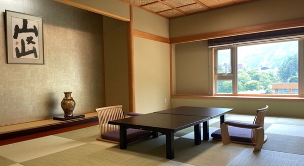 Una tradizionale stanza giapponese con pavimenti in tatami, un tavolino e una finestra che si affaccia sul verde.