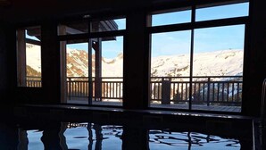 Une piscine intérieure avec de grandes baies vitrées donnant sur des montagnes enneigées.
