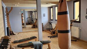Une salle de sport avec un plancher en bois, du matériel d’exercice et un sac de frappe.