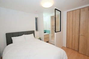 A bedroom with a bed, a wardrobe, and a bathroom visible through an open door.
