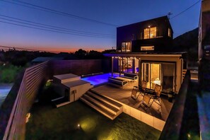 A modern house with a patio, outdoor seating, and a pool.
