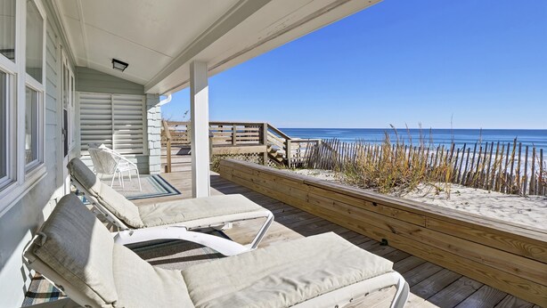 Un espacio al aire libre techado con sillones de descanso y vista a la playa.