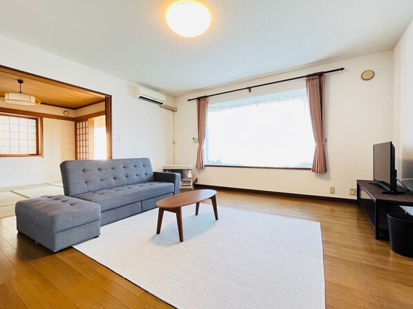 A modern living room with a grey sofa, a wooden coffee table, and a TV on a stand.