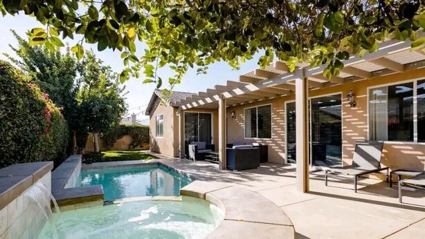 Un jardin avec une piscine, des meubles de patio et un espace salon abrité.