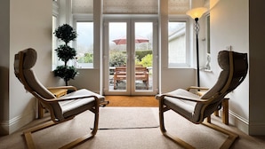A room with two rocking chairs, a potted plant, and a view of the outdoors through a glass door. - 2 Shanklin Manor (Shanklin)