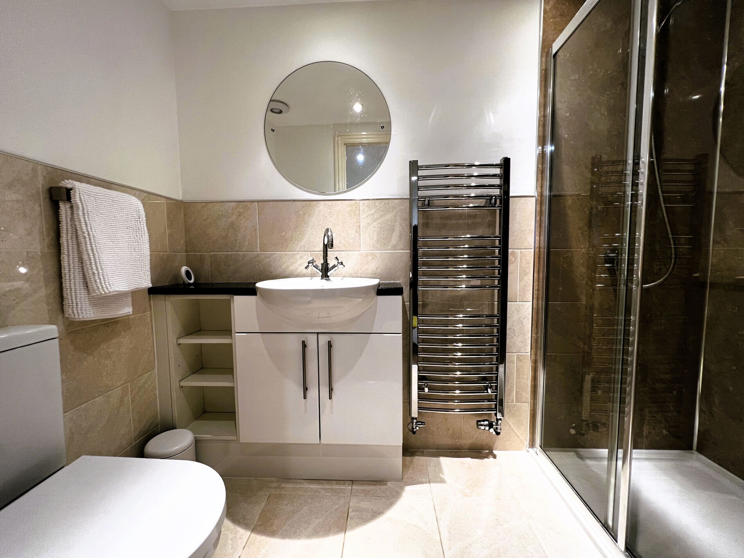 A modern bathroom with a sink, mirror, towel rack, and shower.