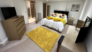 A bedroom with a bed, a TV, a dresser, a mirror, and a yellow rug. - 2 Shanklin Manor (Shanklin)