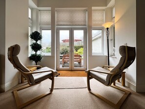 Relax in a serene space with a comfortable seating area, outdoor access, and a touch of greenery.