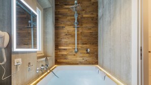 A modern bathroom with a large bathtub, wooden wall paneling, and a showerhead. - Adelante Rooms (Rome)