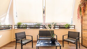 A balcony with two chairs, a table, and potted plants. - Adelante Rooms (Rome)