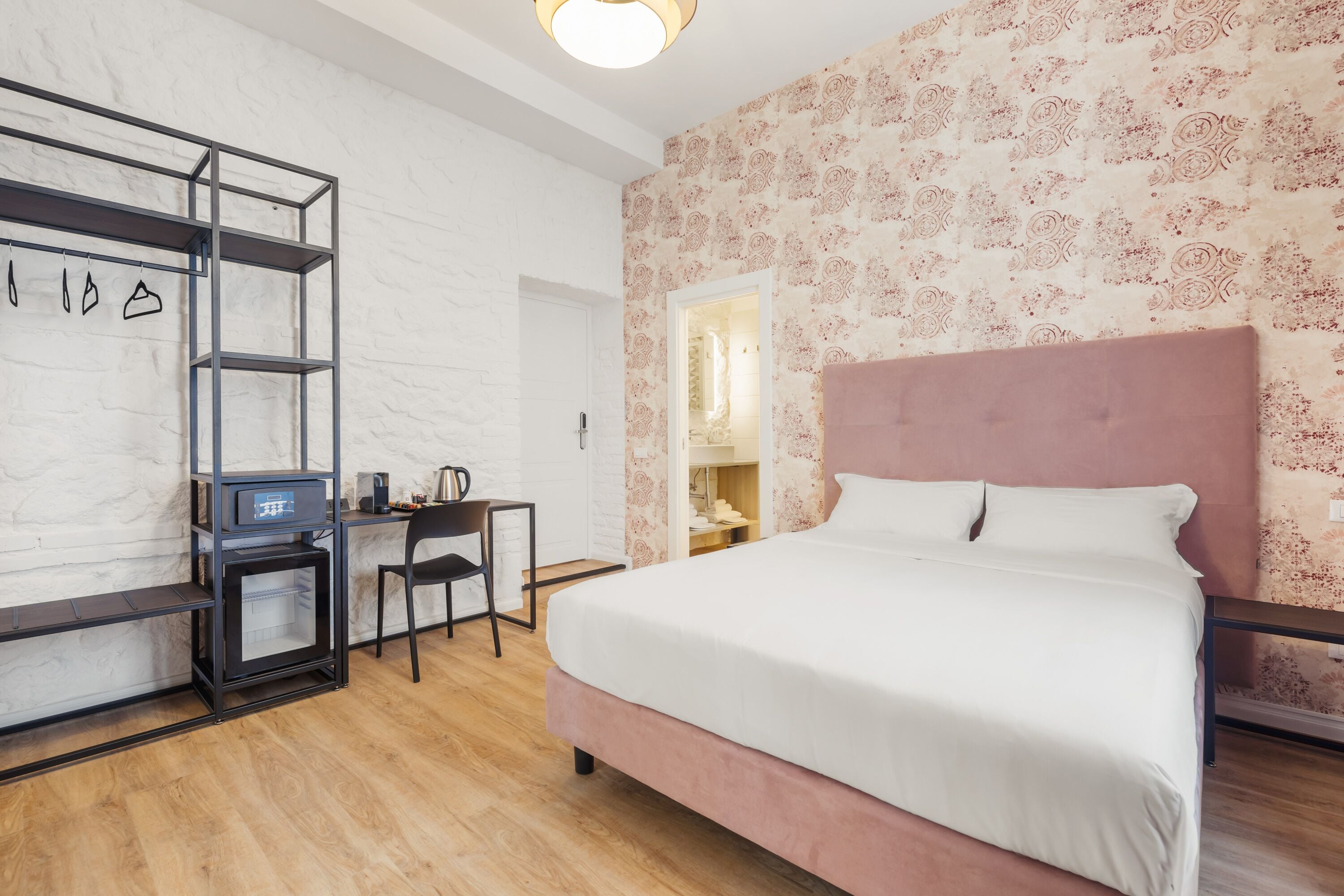 A bedroom with a large bed, a desk with a chair, and a wardrobe.