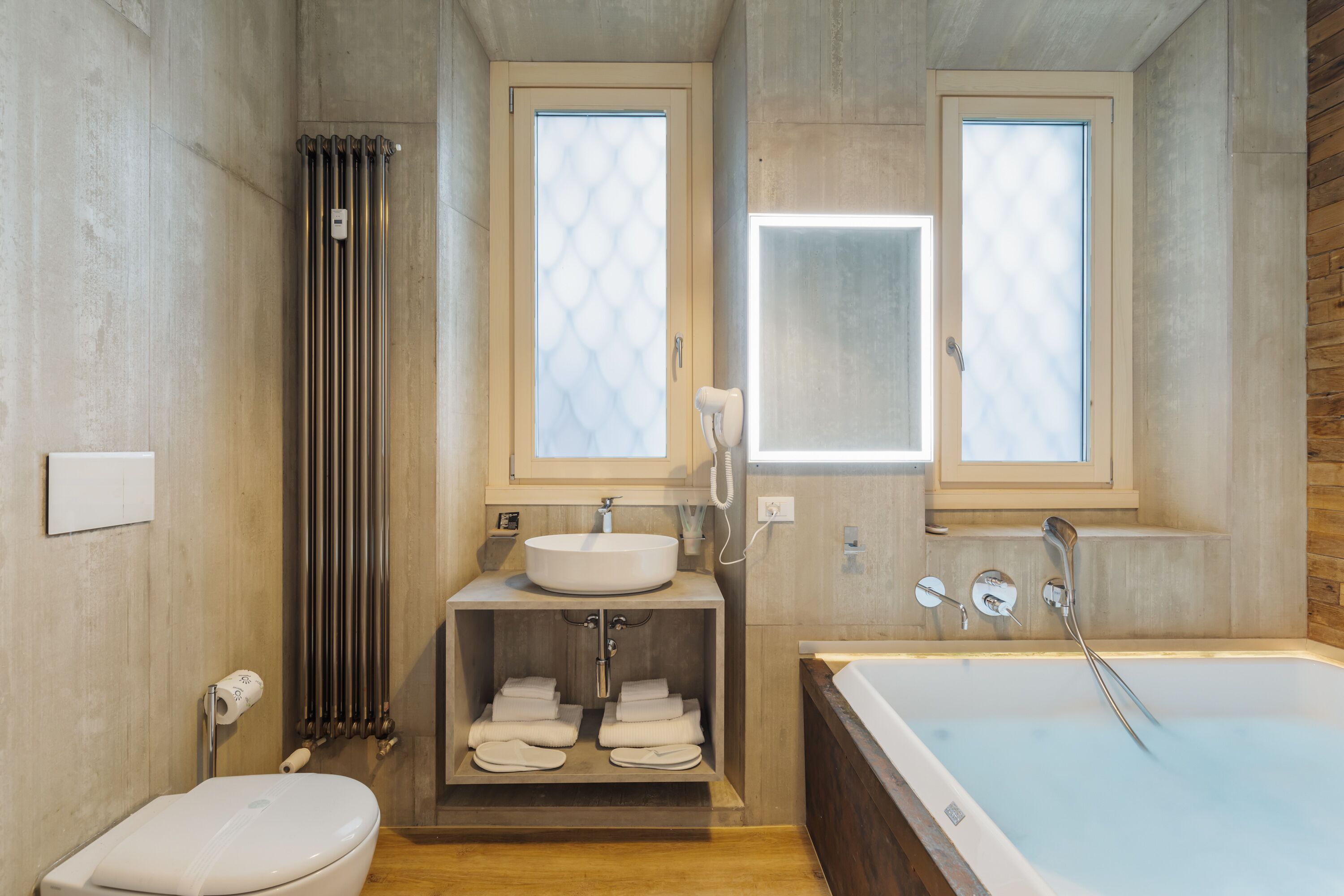 Une salle de bain moderne équipée d’une baignoire, de toilettes, d’un lavabo et d’un porte-serviettes.