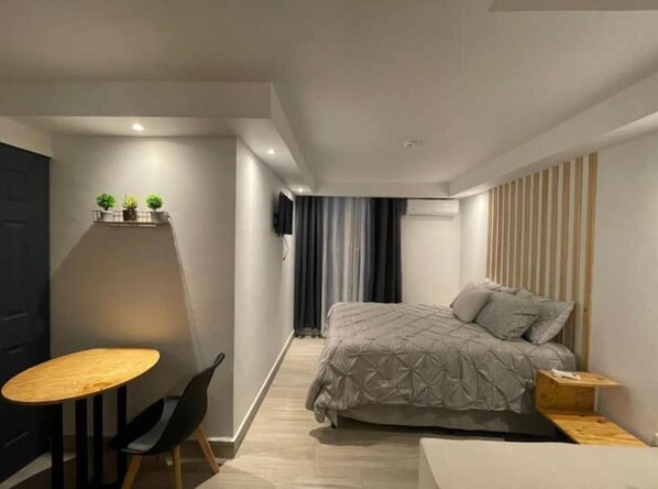 Une chambre à coucher moderne avec un lit, une petite table et une chaise.
