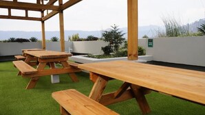 Un patio con mesas de picnic de madera y césped.