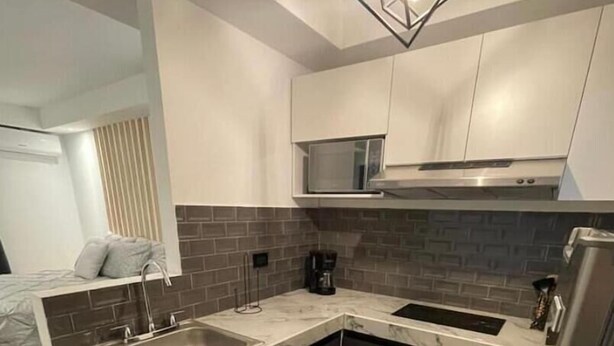 Una cocina moderna con una isla central, armarios oscuros y encimera de color claro.