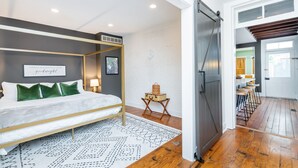 A modern bedroom with a four-poster bed, a bedside table with a lamp, and a wall-mounted air conditioner.