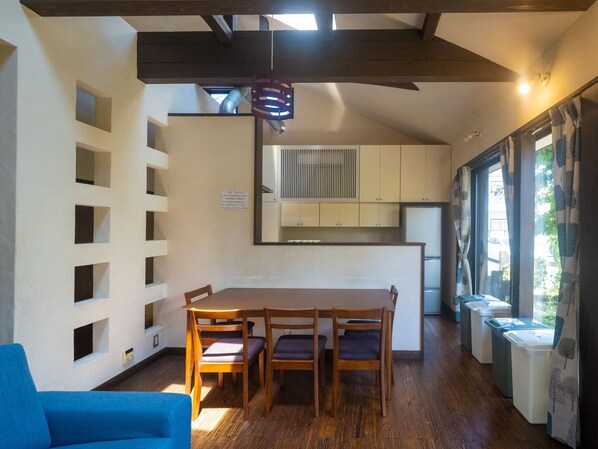 Eine kleine Küche mit Essbereich, Holzkohlenstühle, ein blaues Sofa und ein Deckenventilator.