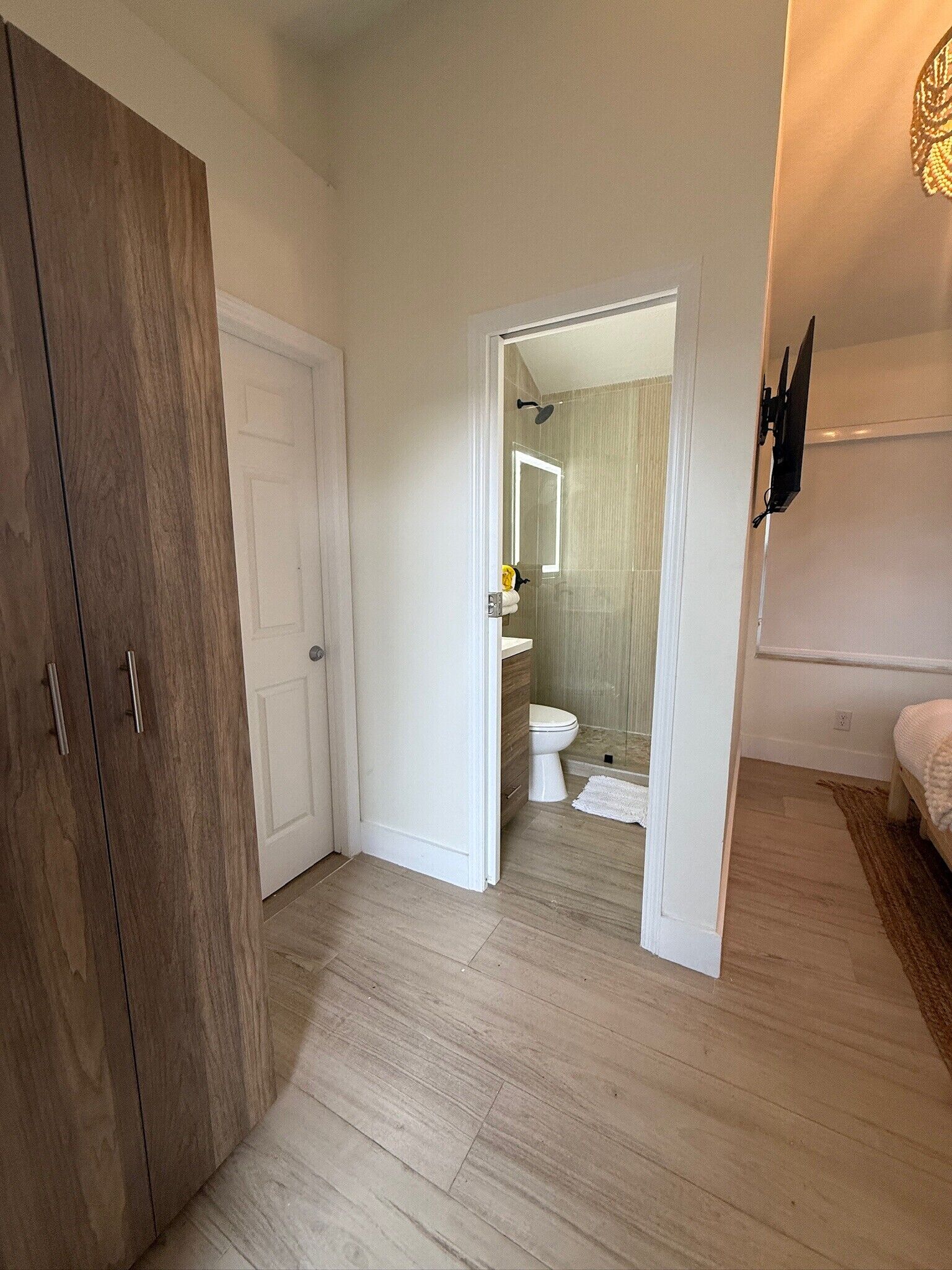 Un dormitorio con un armario de madera, una cama y un baño con inodoro y ducha.
