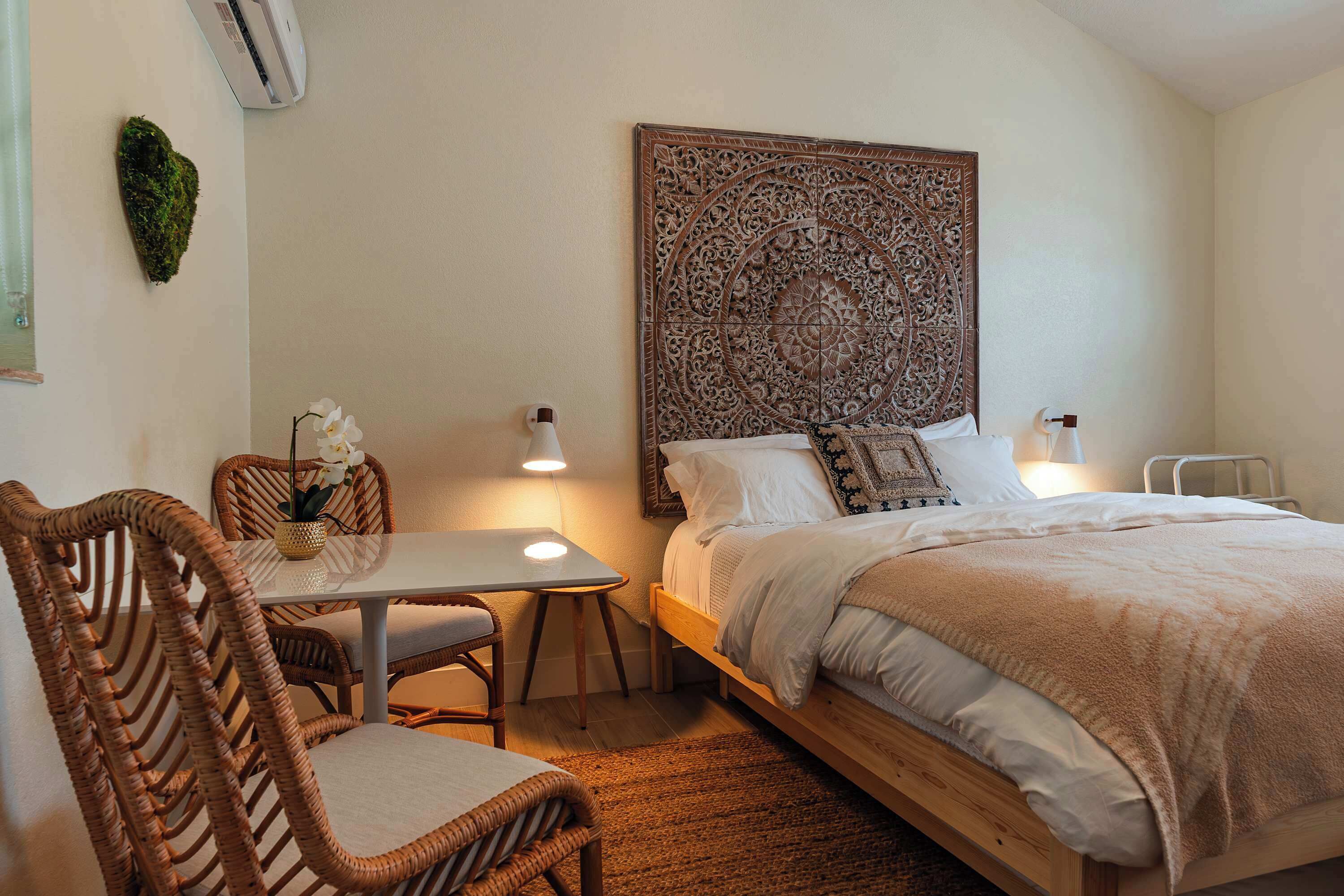 Une chambre à coucher comprenant un lit, une table de chevet, une chaise et un climatiseur fixé au mur.