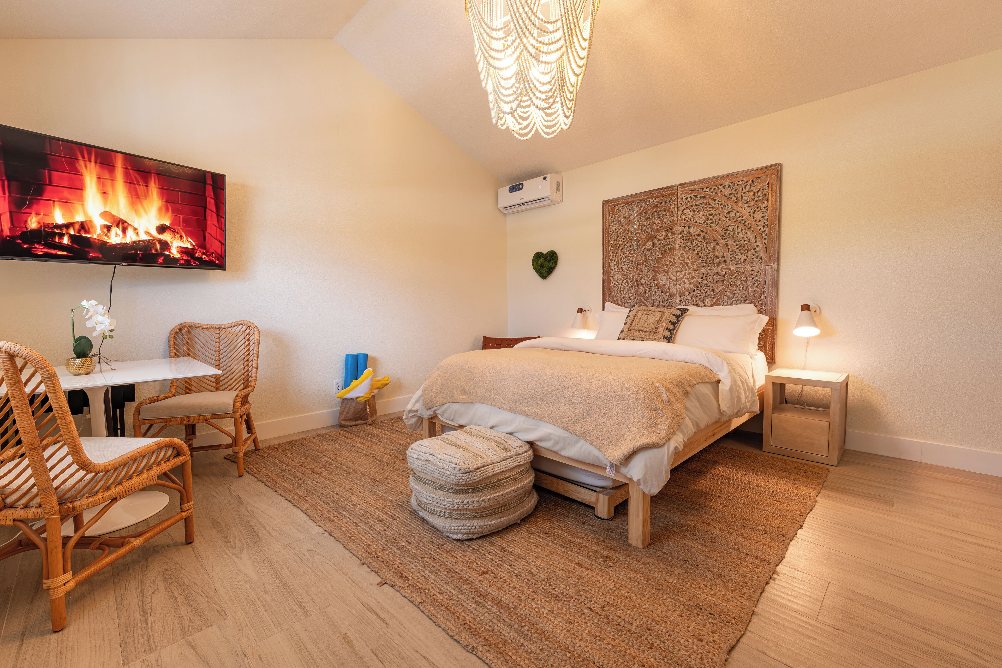A bedroom with a bed, bedside tables, a TV, and a wall-mounted air conditioner.