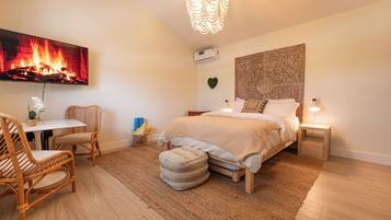 A bedroom with a bed, bedside tables, a TV, and a wall-mounted air conditioner.