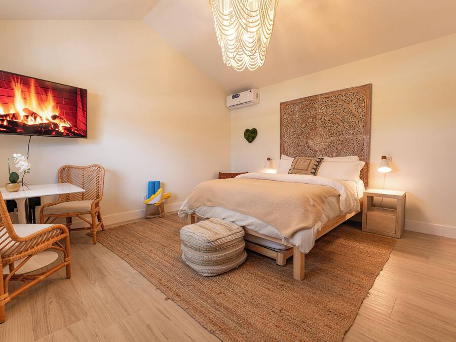 A bedroom with a bed, bedside tables, a TV, and a wall-mounted air conditioner.