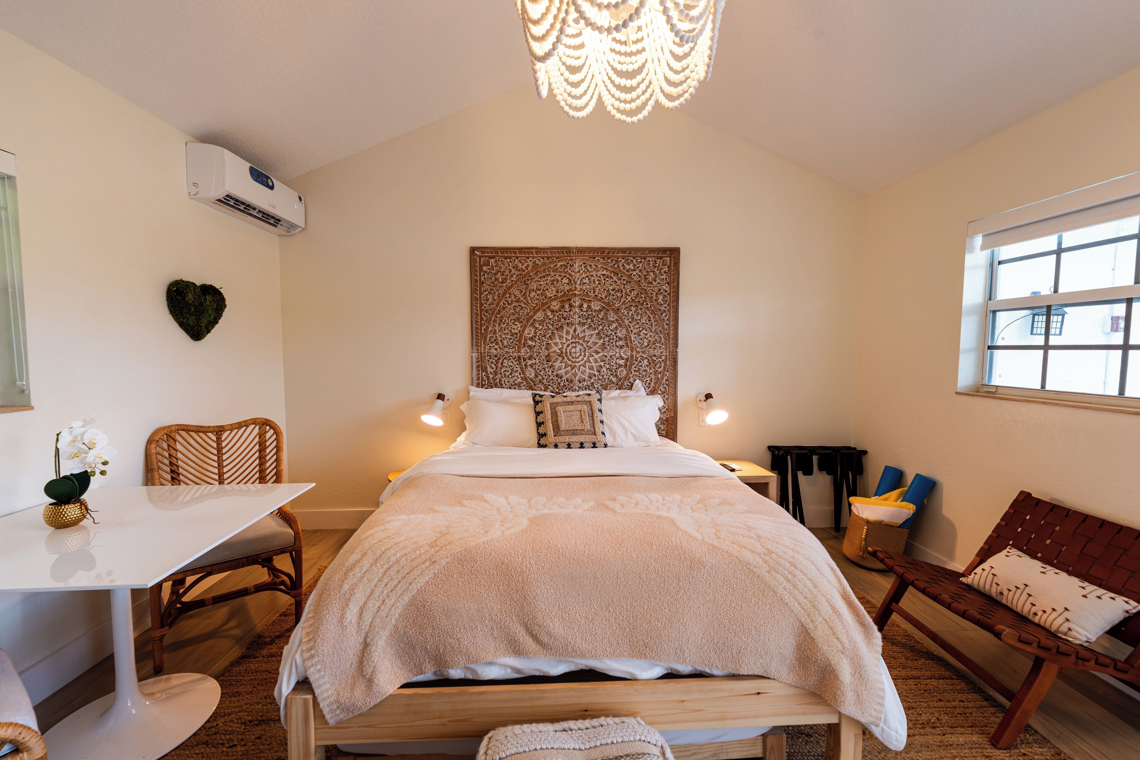 A neatly arranged bedroom with a bed, bedside tables, a chair, a desk, and a window.