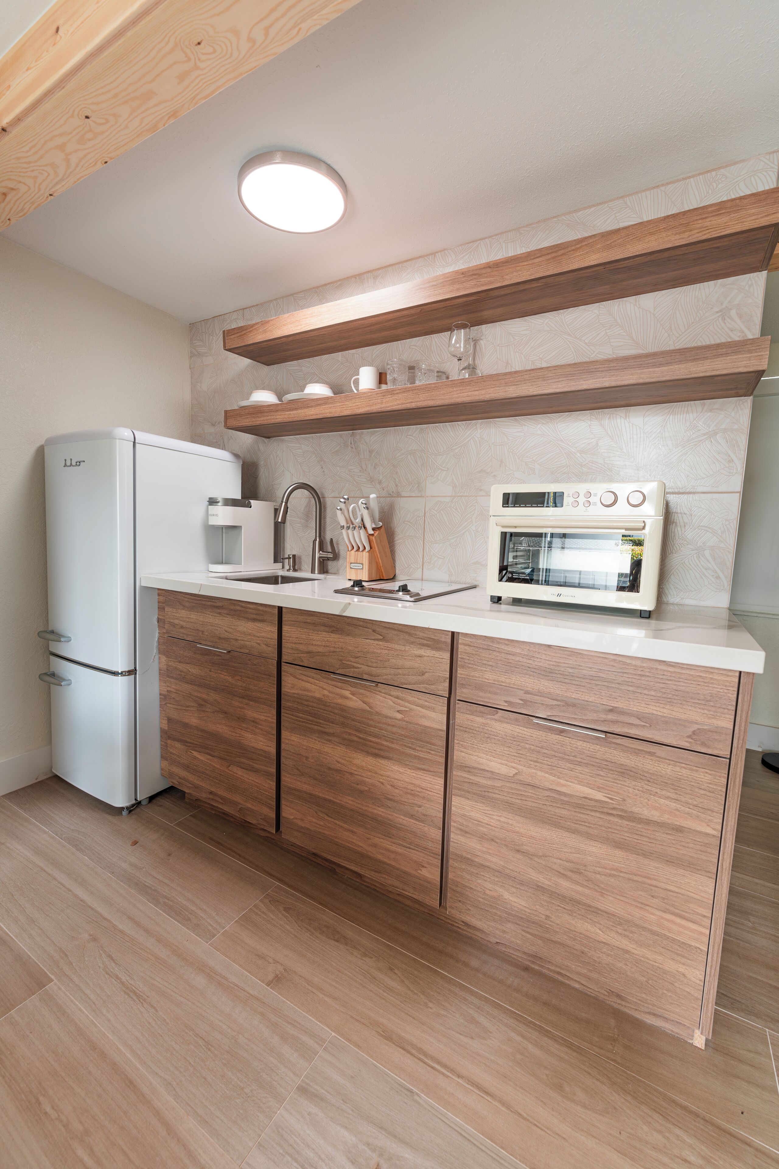 Una cocina moderna con refrigerador, microondas y horno integrados, armarios de madera y encimera.