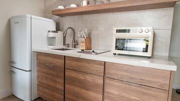 Una cocina moderna con refrigerador, microondas y horno integrados, armarios de madera y encimera.