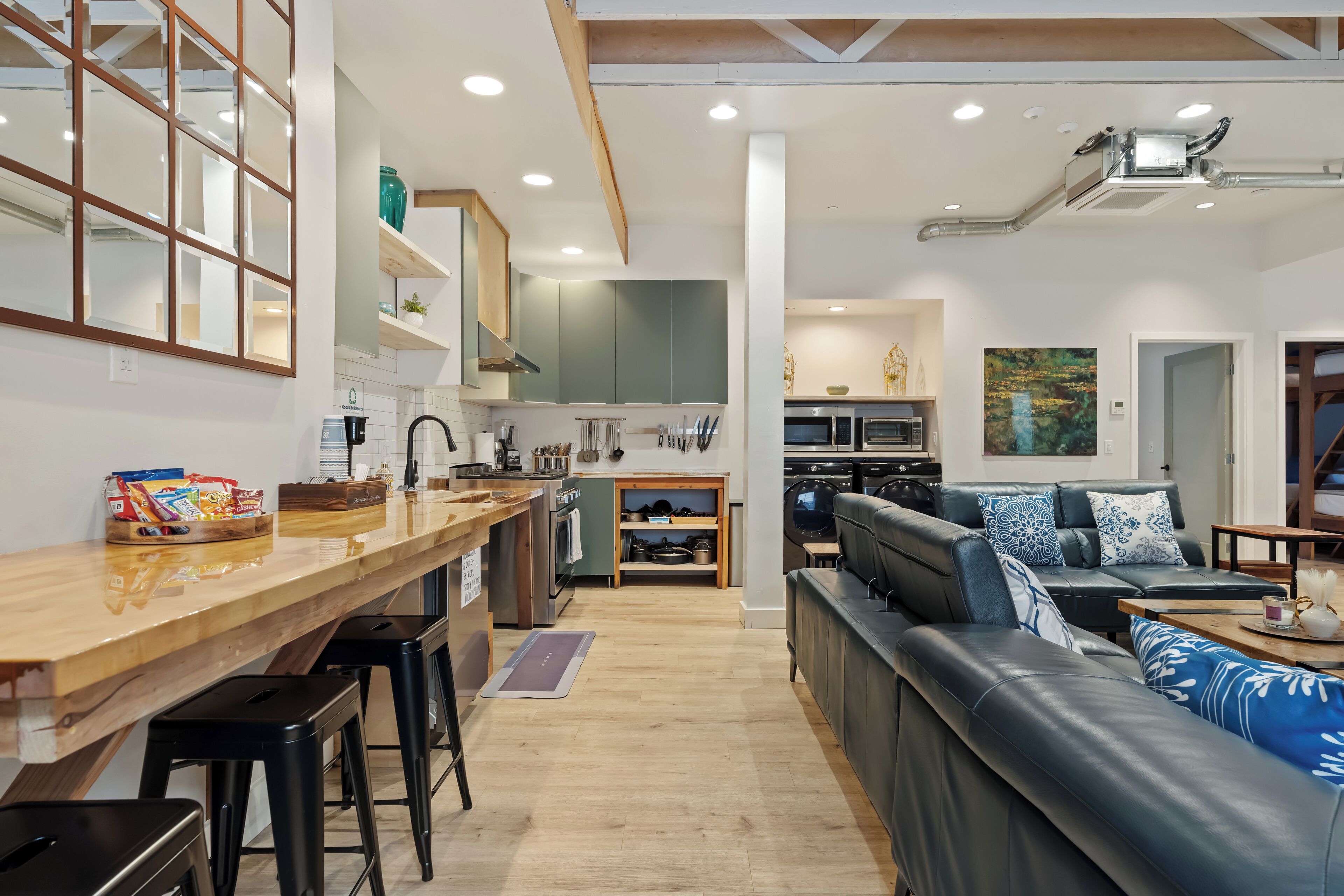 A modern kitchen with wooden countertops, a built-in oven, and a dining area with a long table and bar stools.