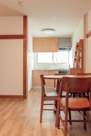 A modern kitchen with wooden cabinets, a dining table with chairs, and a window providing natural light. - 3 minutes walk to Tokyo Metro Namboku Line Oji Ka / Kita-ku Tokyo (Kita-ku)
