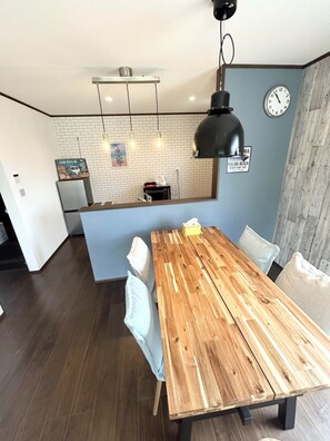 Eine moderne Küche mit weißer Ziegelrückwand, einem Holzespeisetisch mit vier Stühlen und einer Uhr an der Wand.