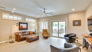 A spacious living room with a brown leather sofa, a tan armchair, and a black leather chair. There is a ceiling fan, a glass coffee table, and a wooden dining table with chairs. - Hike & Golf! Extended Surprise Stay w/ Pool Access (Surprise)