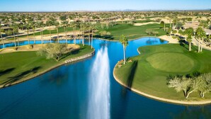 A golf course with a large pond, palm trees, and a waterfall. - Hike & Golf! Extended Surprise Stay w/ Pool Access (Surprise)