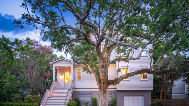A two-story house with a large tree in front, a staircase leading to the entrance, and a well-maintained lawn. - 5BR 4.5 BA Beach House close to beach on IOP with Private Pool! (Isle of Palms)